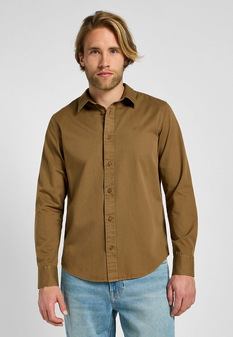 Camisa de manga larga marrón con botones en el frente, que presenta un cuello clásico, botones marrones y un logo sutil en el pecho.