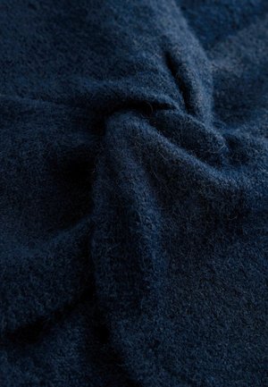 Marinblått, texturerat tyg, mjukt och fluffigt, med en svag lyster. Materialet har ett fint, vävt mönster som skapar djup och visuell intressanthet.