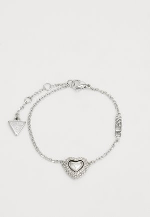 Silberne Kettenarmband mit einem herzförmigen Mittelpunkt, der mit Strasssteinen verziert ist. Inklusive einer Markenanhänger und einem Karabinerverschluss.