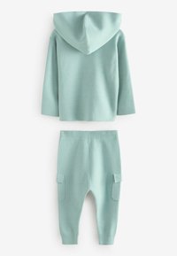 Mintgrön hoodie med huva och långa ärmar, i kombination med matchande tapered byxor med fickdetaljer. Mjuk textur.
