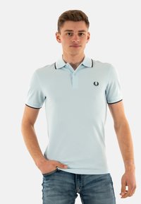 Polo shirt azzurro chiaro con colletto e polsini in contrasto blu scuro, caratterizzato da un piccolo logo sul petto e un design classico.