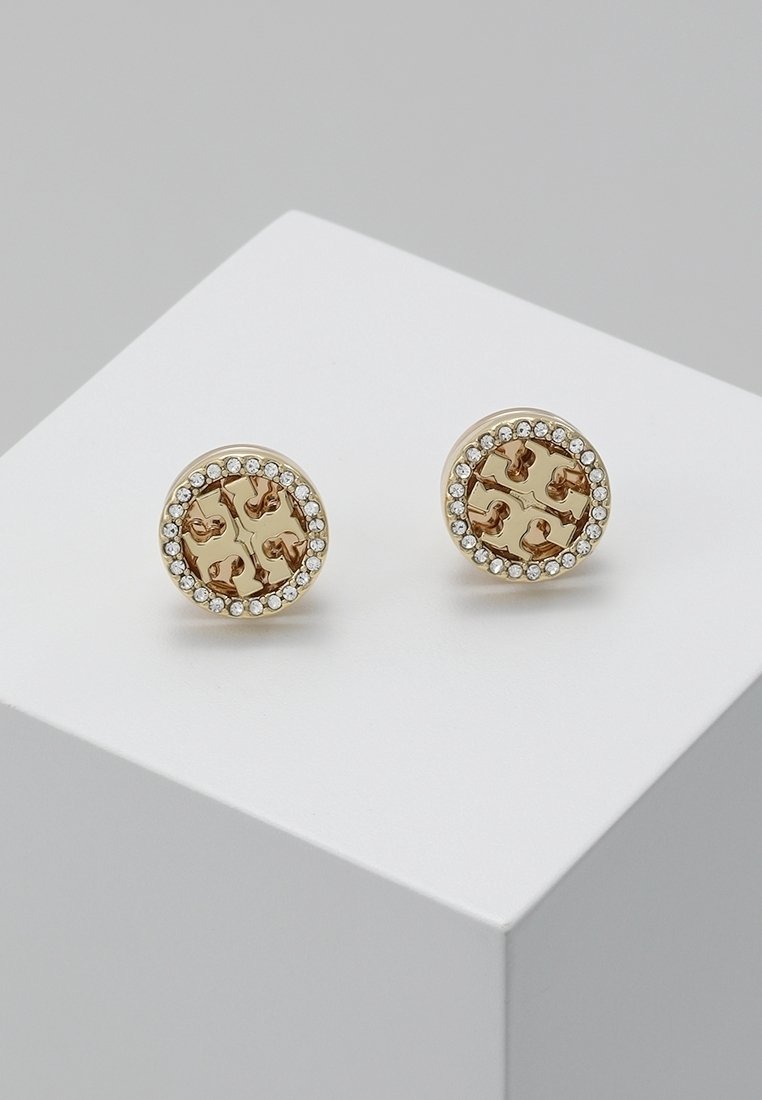 Boucles d'oreilles clous rondes en or avec un motif de croix découpé, bordées d'un cercle de petits cristaux clairs sur une surface blanche.