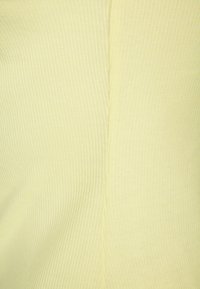 Ljust gult ribbat tyg med en mjuk textur och en slät yta, med vertikala linjer längs ytan.