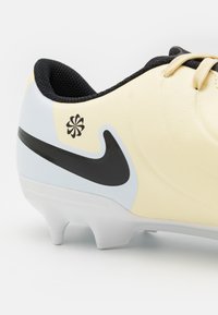 Yellow soccer shoe with black accents and a light blue panel. Features textured upper, laces, and a prominent black Nike logo on the side.
