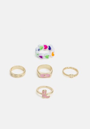 Conjunto de cinco anéis, incluindo uma faixa com padrão de corações multicoloridos, anéis de ouro com pedras preciosas e um detalhe rosa, exibindo variados designs e texturas.