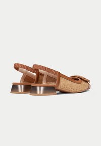 Zapatos slingback de color marrón, tejidos, con puntera redonda, banda elástica y un tacón bajo metálico. Material texturizado y un detalle de lazo en la parte frontal.