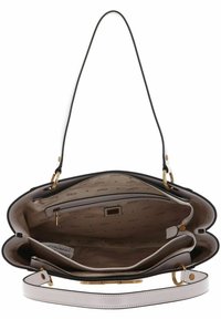 Borsa bianca e nera con hardware dorato. L'interno presenta varie tasche e un rivestimento beige con un motivo ripetuto "GUESS".