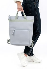 Grijze totebag met een matte afwerking, voorzien van lichtgroene banden, een voorvak met rits en verstelbare schouderbanden. Getextureerd materiaal.