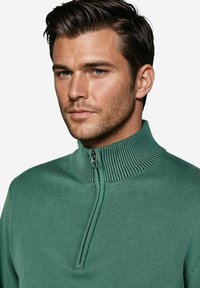 Grüner Pullover mit Reißverschluss und strukturiertem Stehkragen; aus glattem Stoff gefertigt. Verfügt über einen Reißverschluss in Viertellänge. Eng anliegendes Design.