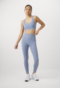 Light blue athletic set featuring a cropped top and high-waisted leggings. The fabric has a smooth texture, paired with white sneakers.