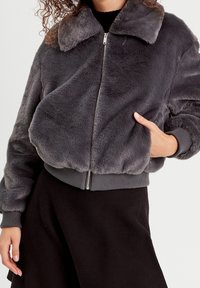 Gray faux fur bomber jacket with a zip front, ribbed cuffs and hem, and a collar. Soft texture with a loose fit design.