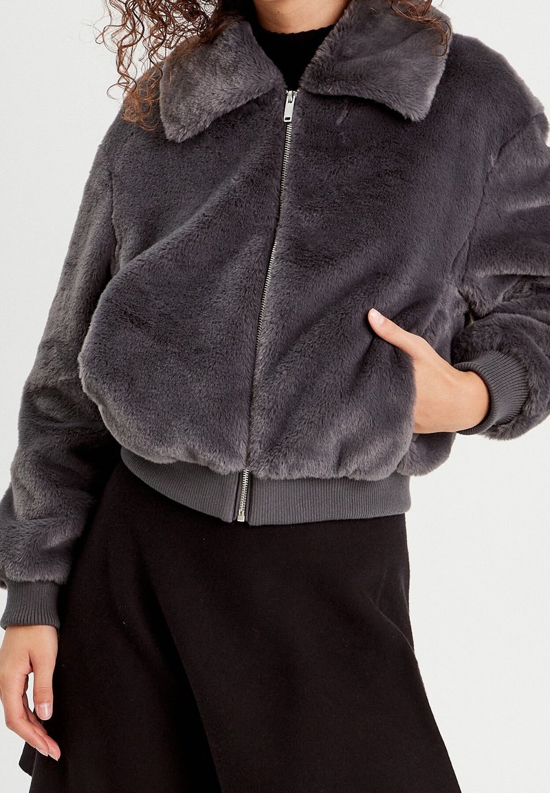 Gray faux fur bomber jacket with a zip front, ribbed cuffs and hem, and a collar. Soft texture with a loose fit design.