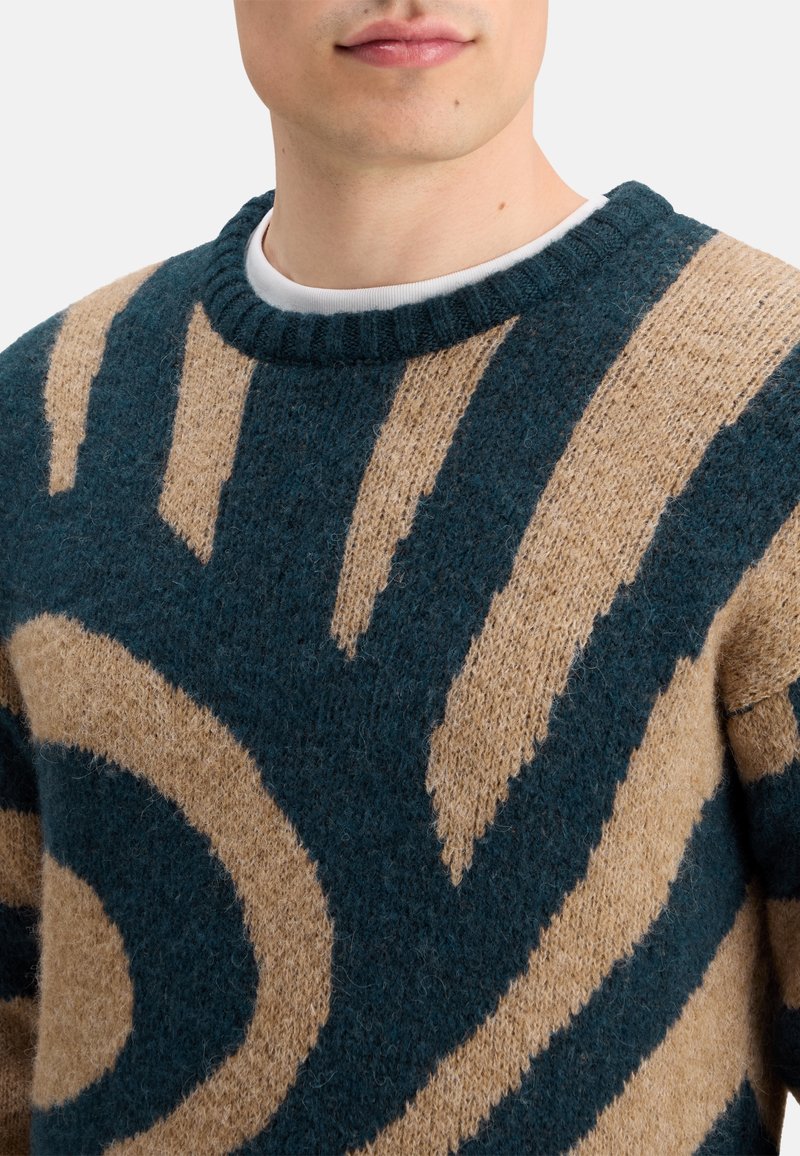 Strickpullover mit einem türkisfarbenen Hintergrund und hellbraunen abstrakten Mustern. Der Stoff ist strukturiert und weich, mit einem Rundhalsausschnitt.
