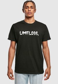 Svart bomull t-skjorte med ordet "LIMITLESS." i fet hvit, teksturert font; kort erm og rund halslinning.