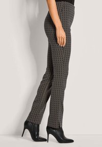 Zwart-wit gestreepte broek met een slim fit, voorzien van een zigzagpatroon, gecombineerd met zwarte hoge hakken. Soepele structuur.