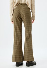 Braune und beige Hahnentrittmuster Hosen mit weitem Bein, einem figurbetonten Bund, seitlichen Taschen und einer glatten Textur. Schwarze Schuhe runden den Look ab.