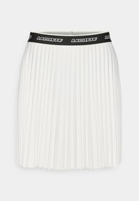 Jupe plissée blanche avec une taille élastique noire arborant le logo "LACOSTE" en blanc. Texture lisse et silhouette droite.