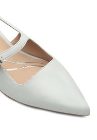 Chaussure en cuir bleu clair avec un bout pointu et des découpes sur les côtés. Des accents en argent rehaussent le design. Texture lisse avec une finition mate.