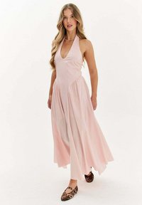 Ružové maxi šaty s halter výstrihom a hlbokým V vystrihom, s zhromaždenými bokmi a voľnou sukňou. Nosí sa s balerínkami s leopardím vzorom.