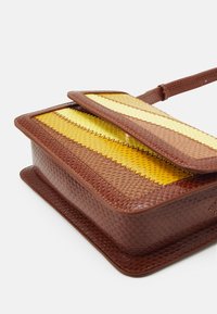 Bolso de piel marrón texturizada con cierre de solapa que presenta un diseño de rayas amarillas y marrones. Forma rectangular compacta con una correa delgada.