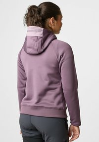 Paarse fleece hoodie met een aansluitend ontwerp, voorzien van een capuchon en een gestructureerde stof. Logo zichtbaar op de achterkant. Gecombineerd met donkergrijze shorts.