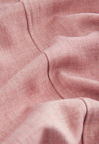 Kangasnäpp i mjuk rosa nyans med en lätt texturerad väv; visar försiktiga veck och en slät, inbjudande yta.