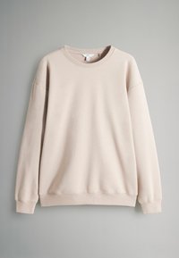 Jasno beżowa bluza z miękkiego materiału. Posiada okrągły dekolt, długie rękawy, ściągacze przy mankietach i u dołu oraz luźny krój.