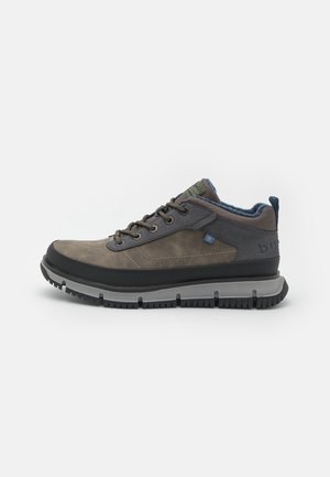 Chaussure de randonnée marron et grise avec une tige en cuir, une semelle extérieure en caoutchouc et des accents texturés. Présente des œillets renforcés et un intérieur bleu.