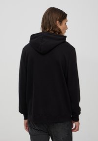 Felpa con cappuccio nera caratterizzata da una texture morbida, taglio dritto e polsini e orlo a costine. Design semplice senza loghi o motivi visibili.