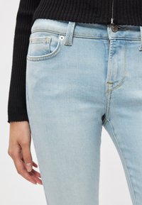 Φωτεινό γαλάζιο τζιν παντελόνι στενής γραμμής, με μέση μέσου ύψους, διακριτική ξεθώριαση και σχέδιο με πέντε τσέπες. Λεπτομέρειες κλεισίματος με φερμουάρ και κουμπί.