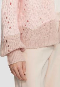 Jasnoróżowy kardigan z dzianiny z teksturowanym, otwartym wzorem i prążkowanymi mankietami. Hem jest lekko skrócony z miękkim wykończeniem.
