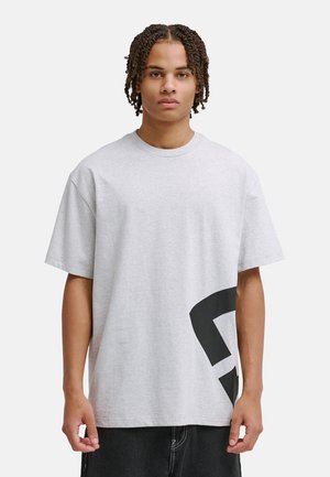 Grijs katoenen t-shirt met een losse pasvorm, ronde hals en korte mouwen; heeft een groot zwart grafisch ontwerp aan de linker onderzijde.