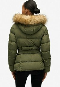 Chaqueta acolchada verde oliva con capucha de pelaje sintético. Presenta una cintura ceñida, diseño acolchado y puños elásticos. Textura suave y apariencia cálida.