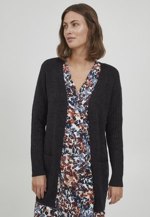 Mörkgrå ribbad cardigan med öppen front, långa ärmar och två framfickor, lagd över en blommönstrad klänning.