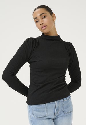 Black long-sleeve top with a high neck, textured fabric, and puffed sleeves, paired with light blue denim jeans.