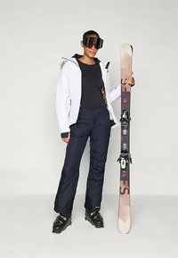 Sífelszerelés, amely egy fehér szigetelt kabátot, fekete nadrágot és egy sílécet foglal magában. Tartalmaz nagy sígépüveget és fekete sícipőt.