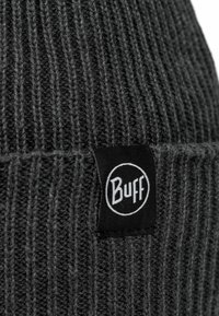Gray knitted beanie with vertical ribbing, featuring a black fabric tag with the "Buff" logo. Textured, warm, and fitted design.