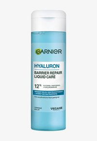 En ljusblå plastflaska med ett vitt lock, märkt "Garnier Hyaluron Barrier Repair Liquid Care," som innehåller produktinformation och ingredienser.