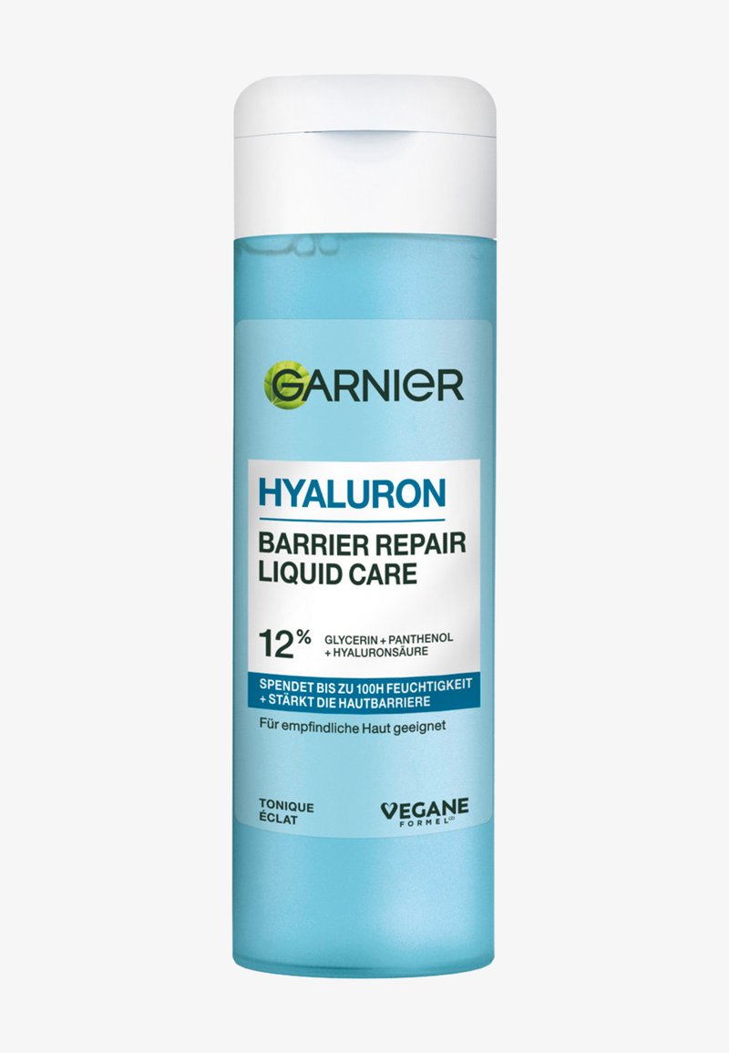 En ljusblå plastflaska med ett vitt lock, märkt "Garnier Hyaluron Barrier Repair Liquid Care," som innehåller produktinformation och ingredienser.
