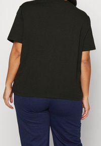 Camiseta de algodón negra con un corte relajado, mangas cortas y escote redondo, que presenta una textura suave y un diseño minimalista.