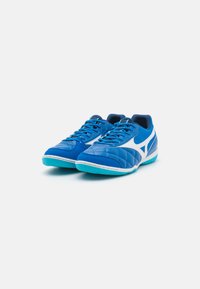 Zapatillas deportivas azules con textura acolchada, acentos blancos y suelas azul claro. Presentan cordones estándar y un diseño de perfil bajo.