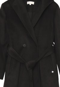Cappotto di lana nera con colletto a scialle, design doppiopetto, vita con cintura e tasche laterali. Presenta un piccolo dettaglio con logo.