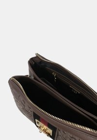 Borsa a tracolla in pelle marrone con superficie testurizzata, zip dorata e interno suddiviso in due comparti, dotato di una tasca con zip.
