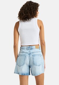 Lichtblauwe denim shorts met een ontspannen pasvorm, een middelhoog taille en twee achterzakken. Heeft een leren logo patch op de achterzijde van de tailleband.