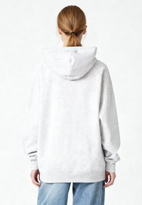 Felpa grigia con cappuccio e vestibilità comoda, caratterizzata da maniche raglan e polsini a coste. Tessuto morbido con una texture liscia.