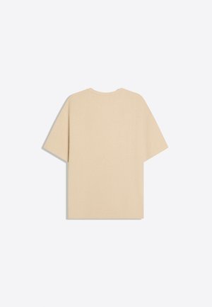 T-shirt beige a maniche corte con coste, distesa e vista da dietro, con scollo rotondo su uno sfondo chiaro.