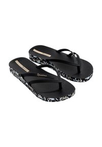 Chanclas negras con plantilla texturizada negra y correas trenzadas. Las suelas presentan un patrón abstracto en blanco y gris, con el logo en la plantilla.