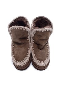 Brune ruskinds slippers med tyk beige syning og mørk plysindtægt, vist ovenfra på en hvid baggrund.