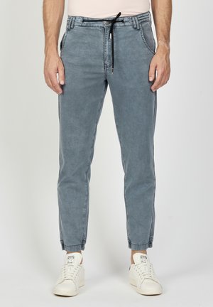 Hellblaue, tapered Hosen mit elastischem Bund, Kordelzugverschluss, seitlichen Taschen und umgeschlagenen Säumen, gefertigt aus einem weichen, leicht strukturierten Stoff.