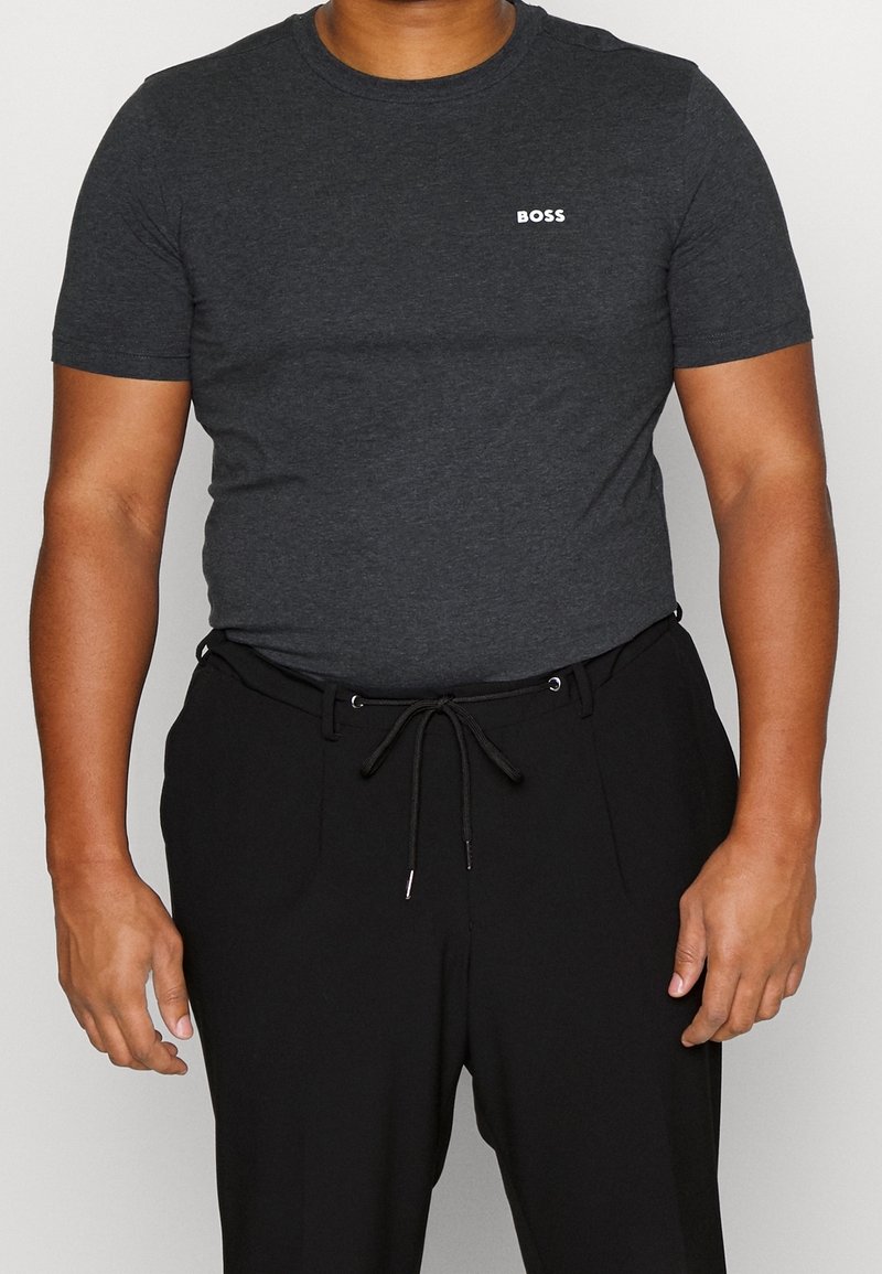 T-shirt ajusté gris charbon à manches courtes arborant un logo "BOSS" blanc sur la poitrine gauche, associé à un pantalon noir à cordon de serrage.